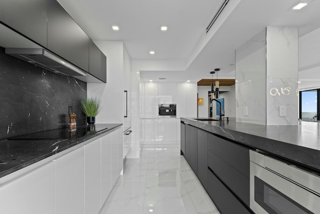 kitchen with marble finish floor, modern cabinets, a sink, stainless steel microwave, and black electric stovetop