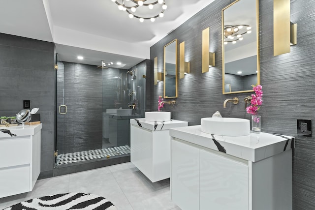 bathroom with tile patterned flooring, a shower stall, two vanities, tile walls, and a sink