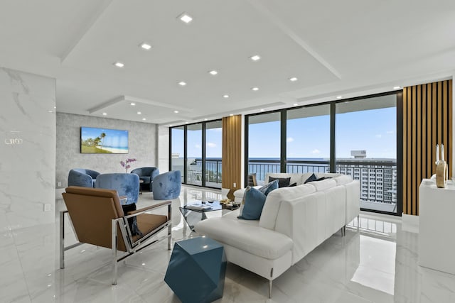 living area with a wall of windows, stone wall, recessed lighting, and marble finish floor