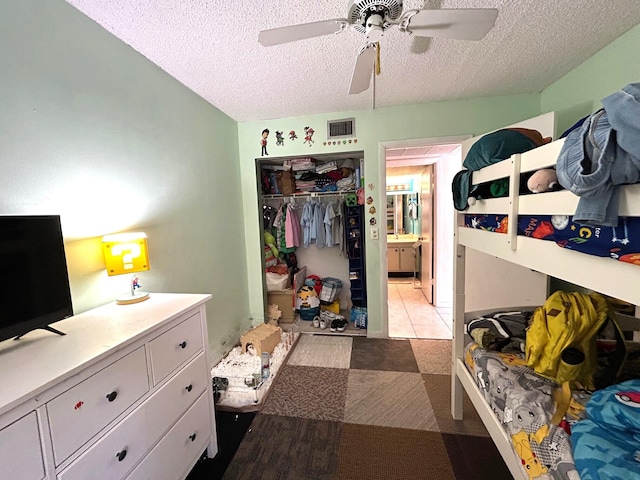 bedroom with a closet, visible vents, a textured ceiling, and a ceiling fan