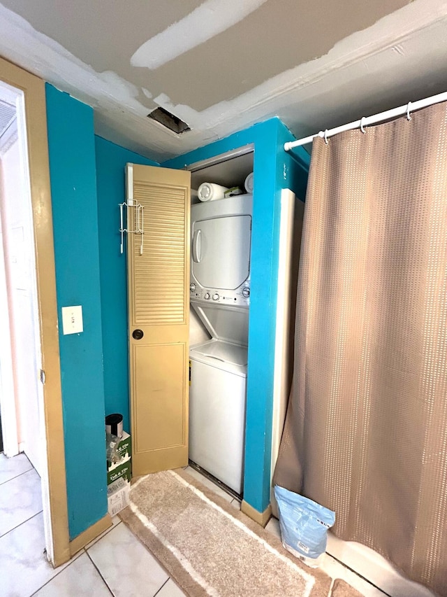 laundry area with stacked washer and dryer, light tile patterned flooring, and laundry area