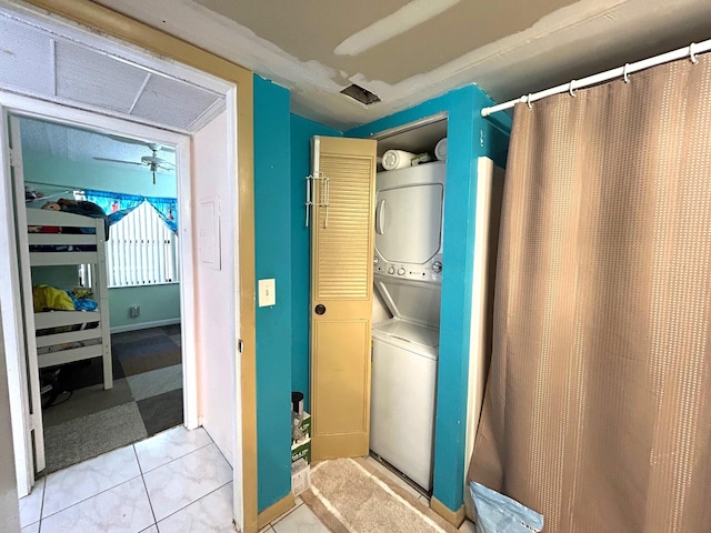 washroom featuring light tile patterned floors, stacked washer and dryer, and laundry area