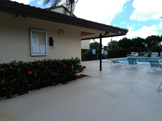 view of patio with a community pool and fence