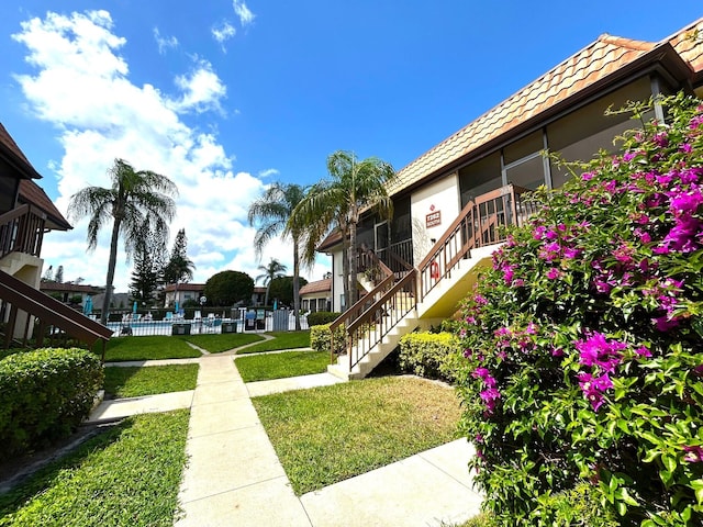 surrounding community featuring a lawn, stairs, and fence