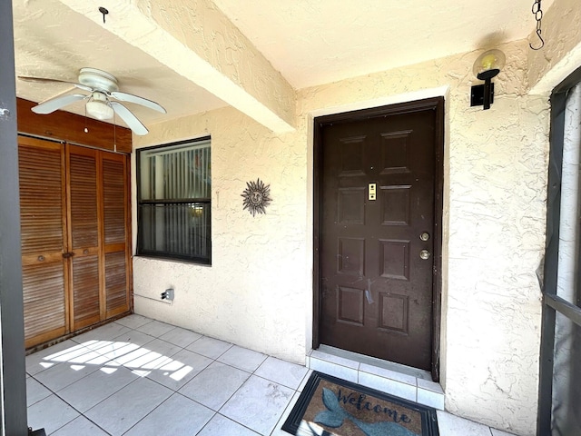 property entrance featuring stucco siding and a ceiling fan