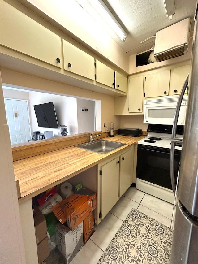 kitchen featuring a sink, a textured ceiling, white appliances, a peninsula, and light tile patterned floors