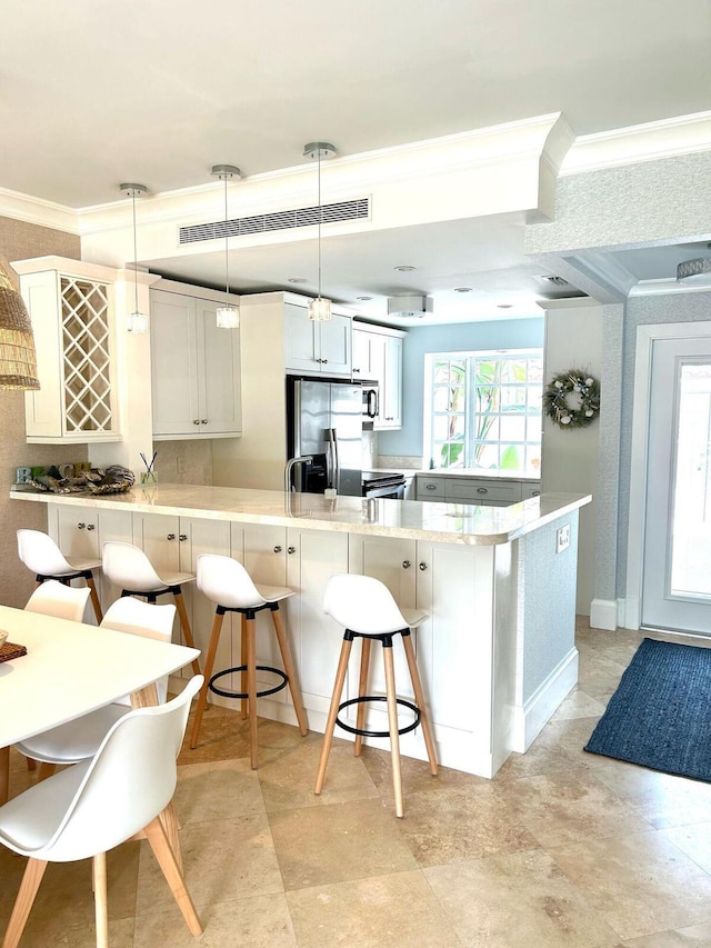 609 NE 19th Ave, Deerfield Beach, FL 33441 - kitchen featuring a peninsula, light countertops, crown molding, a kitchen breakfast bar, and stainless steel fridge