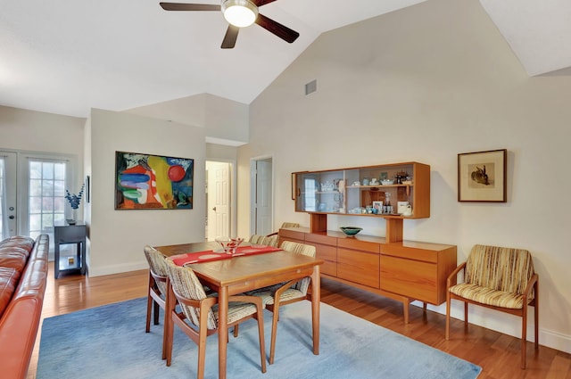 dining room with wood finished floors, a ceiling fan, visible vents, high vaulted ceiling, and baseboards