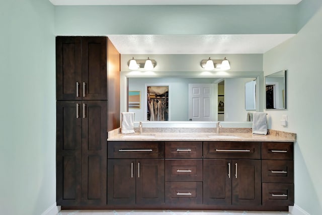 bathroom with double vanity, baseboards, and a sink