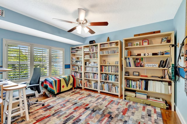 home office featuring a textured ceiling, a ceiling fan, and wood finished floors