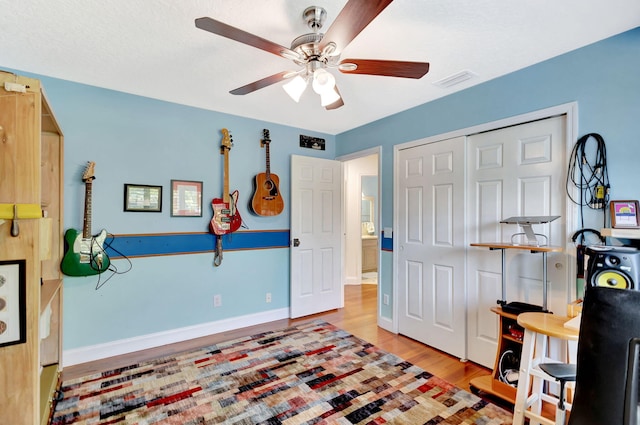 interior space with visible vents, wood finished floors, a closet, baseboards, and ceiling fan