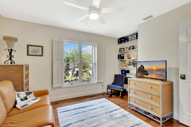 living area with visible vents, baseboards, a ceiling fan, and wood finished floors