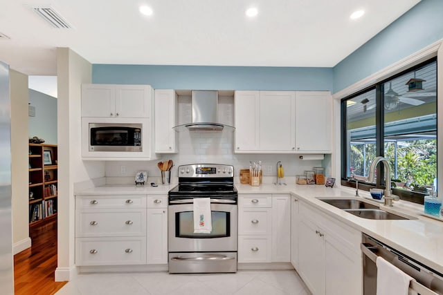 kitchen with visible vents, a sink, stainless steel appliances, white cabinetry, and wall chimney exhaust hood