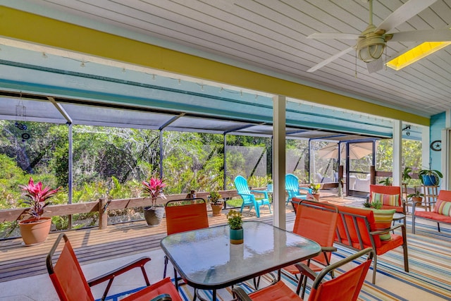 exterior space featuring glass enclosure, outdoor dining area, and ceiling fan