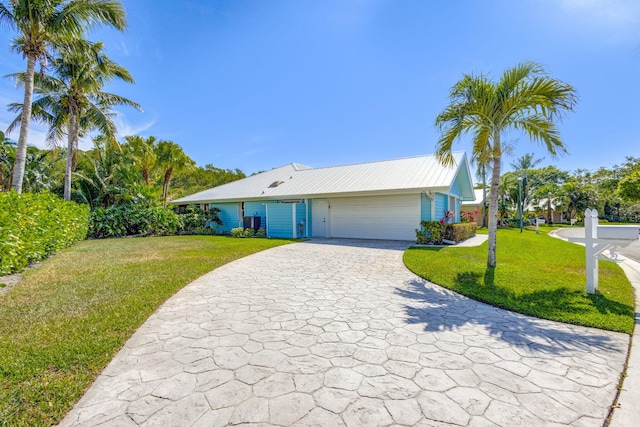 single story home featuring a front lawn, decorative driveway, an attached garage, and metal roof