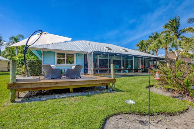 rear view of property featuring a lanai, a lawn, metal roof, and a deck