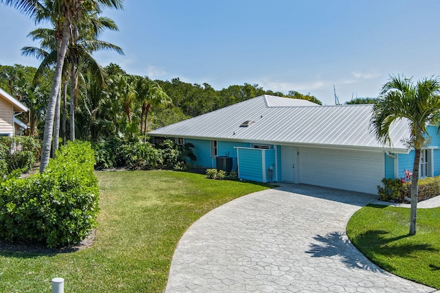 single story home with a front lawn, decorative driveway, central AC, an attached garage, and metal roof