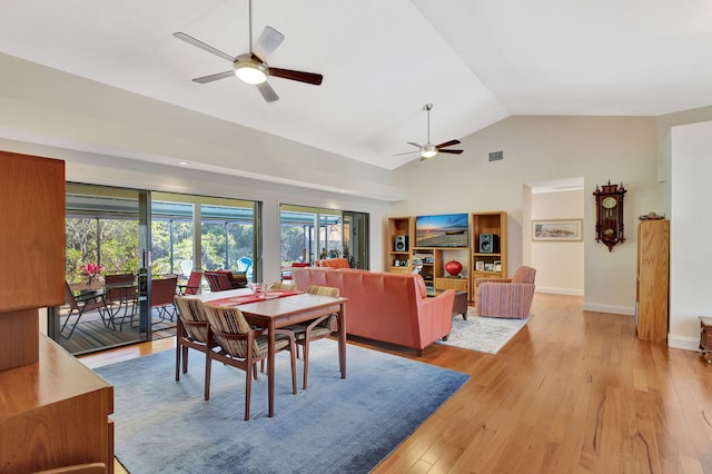 dining space with visible vents, baseboards, light wood-type flooring, high vaulted ceiling, and a ceiling fan