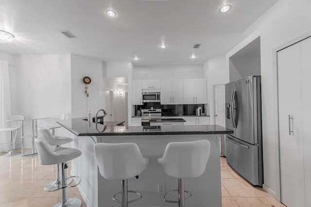 kitchen featuring visible vents, backsplash, appliances with stainless steel finishes, a breakfast bar area, and light tile patterned flooring