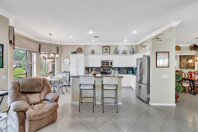 kitchen featuring an inviting chandelier, ornamental molding, white cabinets, appliances with stainless steel finishes, and tasteful backsplash