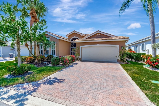 mediterranean / spanish home with a front yard, an attached garage, stucco siding, a tiled roof, and decorative driveway