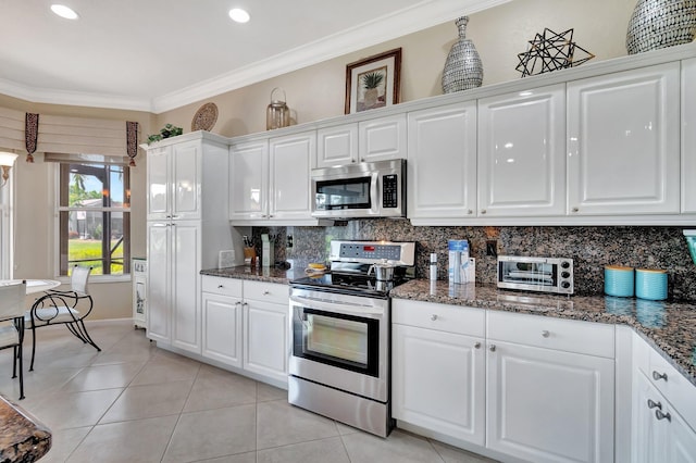 kitchen with light tile patterned floors, appliances with stainless steel finishes, white cabinetry, crown molding, and tasteful backsplash