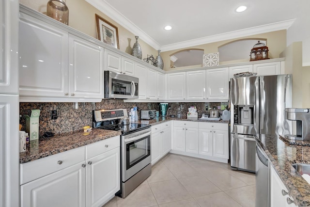 kitchen featuring backsplash, appliances with stainless steel finishes, white cabinetry, and ornamental molding