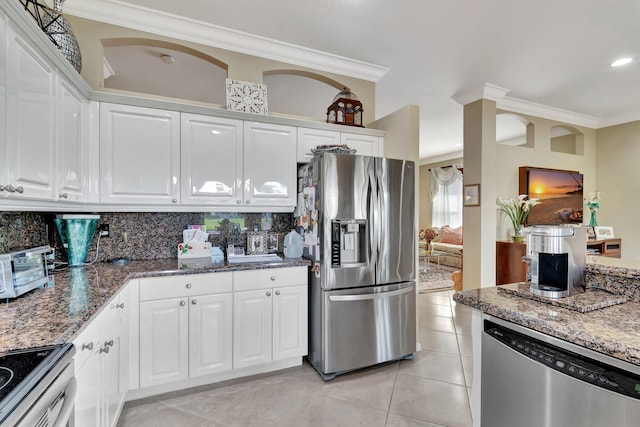 kitchen with ornamental molding, stone countertops, backsplash, white cabinetry, and appliances with stainless steel finishes