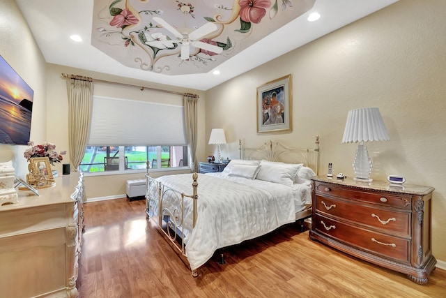 bedroom with recessed lighting, baseboards, a raised ceiling, and wood finished floors