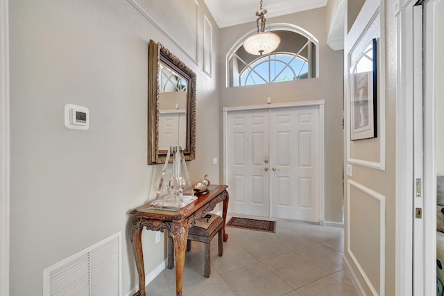 entrance foyer with visible vents, baseboards, ornamental molding, an inviting chandelier, and light tile patterned flooring