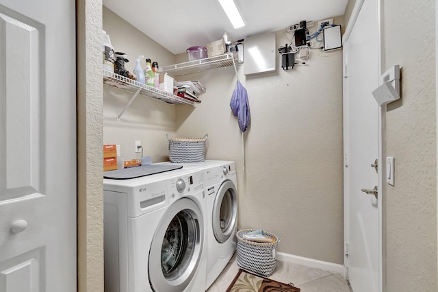 clothes washing area featuring light tile patterned floors, baseboards, washing machine and dryer, and laundry area