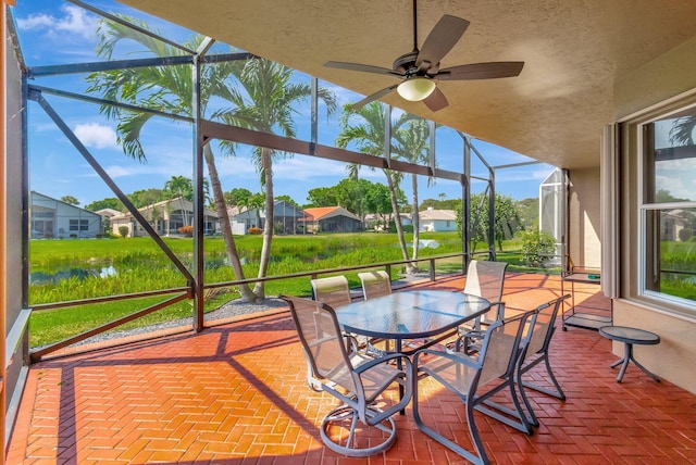 unfurnished sunroom featuring a residential view, a healthy amount of sunlight, and a ceiling fan