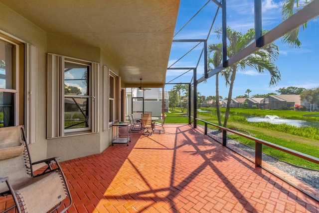 view of patio / terrace featuring glass enclosure and a water view