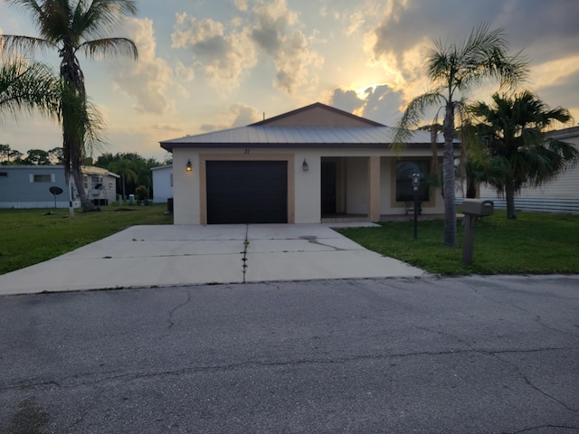 view of front of property with a garage, stucco siding, concrete driveway, and a yard