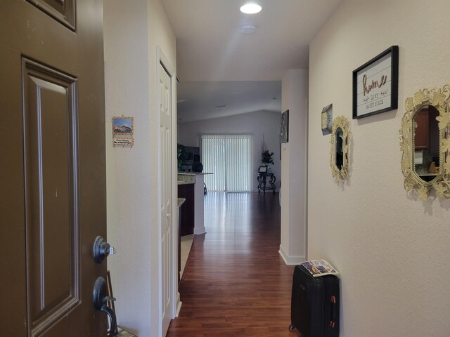 hall with dark wood finished floors, vaulted ceiling, and baseboards