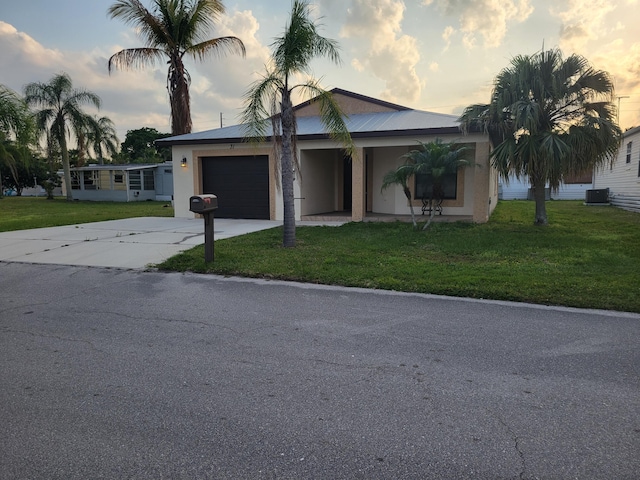 view of front facade with a front lawn, concrete driveway, a garage, and stucco siding