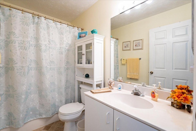 bathroom with a textured ceiling, vanity, and toilet