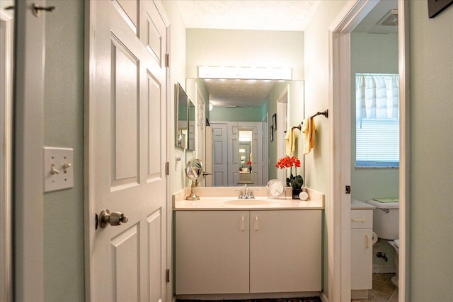 bathroom with visible vents, toilet, vanity, and a textured ceiling