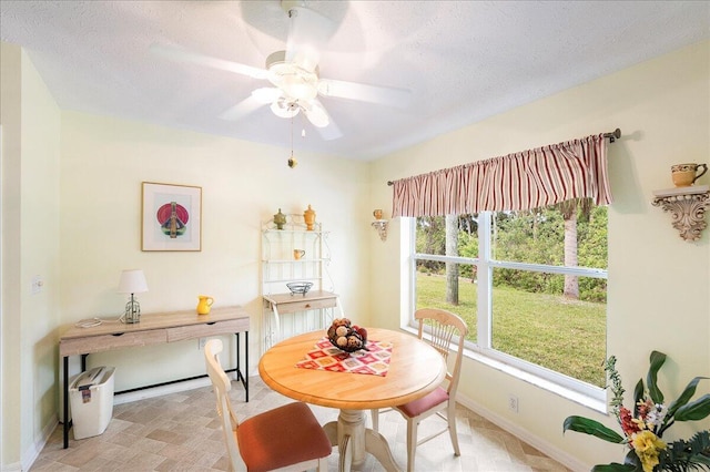 dining area featuring baseboards, a textured ceiling, and ceiling fan