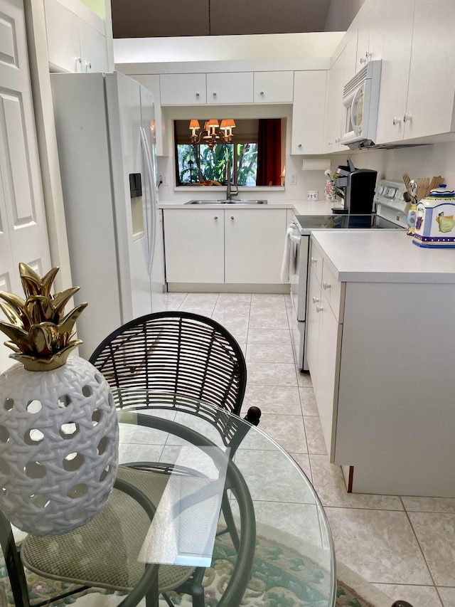 kitchen with white appliances, a notable chandelier, light tile patterned floors, and a sink