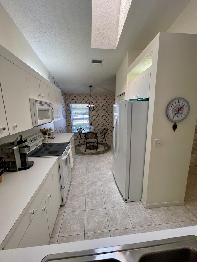kitchen with white appliances, wallpapered walls, light tile patterned flooring, a textured ceiling, and white cabinetry
