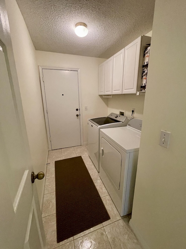 washroom featuring washer and dryer, light tile patterned flooring, cabinet space, and a textured ceiling