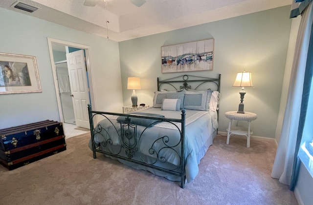 carpeted bedroom with a tray ceiling, baseboards, and visible vents