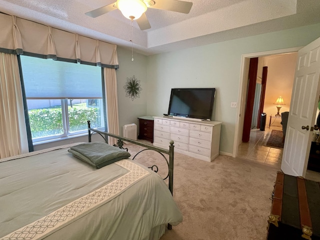 bedroom featuring light carpet, a ceiling fan, a textured ceiling, radiator heating unit, and a raised ceiling