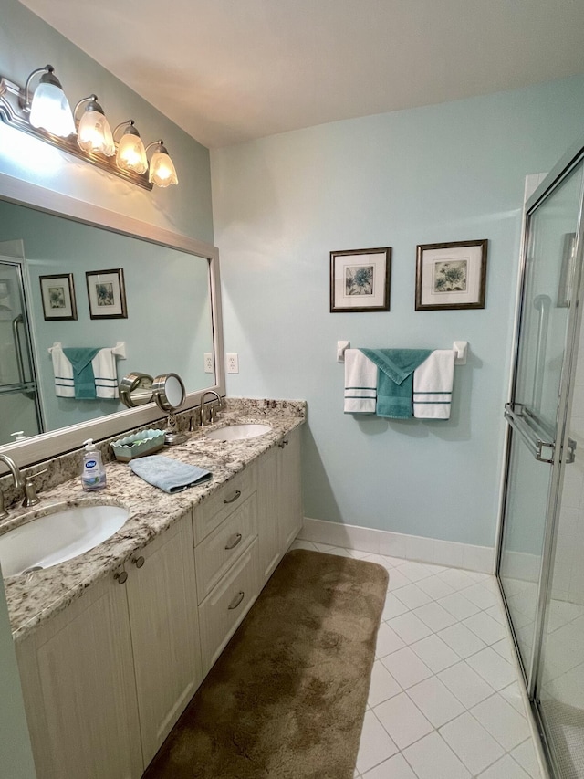 bathroom with a sink, a shower with shower door, double vanity, and tile patterned floors