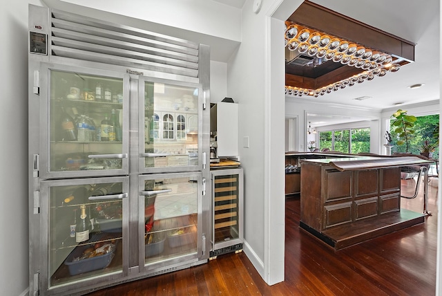 bar featuring wine cooler, bar, and dark wood-type flooring