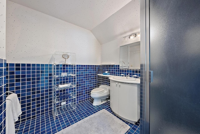 full bath with vanity, lofted ceiling, tile patterned flooring, a walk in shower, and tile walls