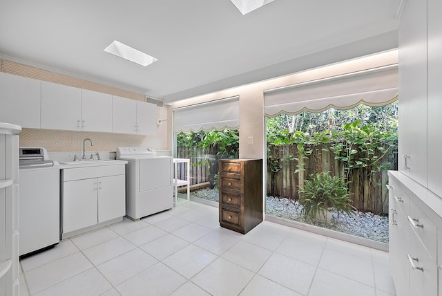 laundry area featuring washing machine and clothes dryer, light tile patterned floors, a skylight, and a sink