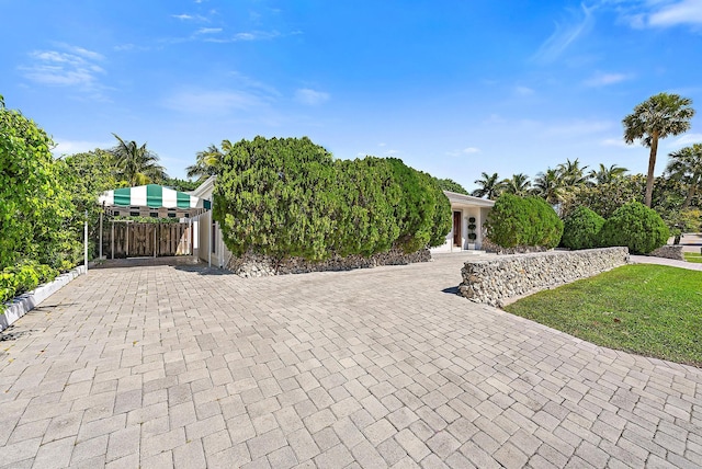 view of front of home featuring a gate, decorative driveway, a front lawn, and fence