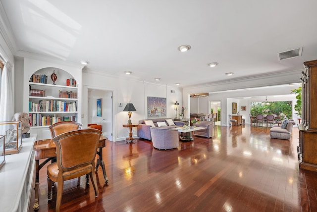 living room with hardwood / wood-style floors, built in features, baseboards, visible vents, and crown molding